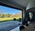 large windows, wooden floor, glass sliding doors leading to terrace, indoor view of a garden