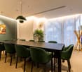 long dining table, green chairs, beige carpet, paintings, lamp, decorative items, curtain