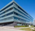 modern office building, grey facade, glass windows, landscaped area in front