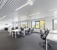 Empty office room with white tables, black chairs, and big windows. Modern office equipment. White walls and ceiling.