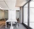 modern office room, white desk, black chairs, glass walls, carpeted floor, sliding glass door