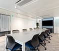 modern office meeting room with glass walls, long table, chairs, TV, plant, whiteboard