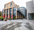 modern office building, glass facade, glass roof, arched entryway, plants and umbrellas on patio