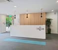 Empty reception area, white countertop, 'Regus' logo, vertical wooden panels, glass doors, pendant lights, potted plant