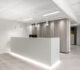 open space, white walls, white ceiling, reception desk, pendant lights, wooden wall, white flooring