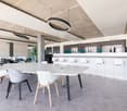 modern office room, large white table, white chairs, white counter, white cabinets, hanging lamps, gray floor