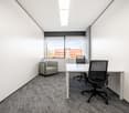 empty room, white walls, white desk, two black office chairs, gray armchair, large window