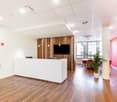 Reception area with desk, wooden floors, plants, monitor and windows