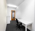 Empty office with desk, wooden door, white walls, grey carpet