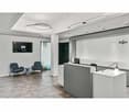 Office space with gray chairs, black TV monitor, reception desk, lamps