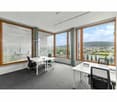 modern office room with large windows, white desks, black chairs, carpeted floor, view of the city