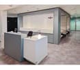 modern office design with gray and white colors, a reception desk with a lamp, a board with 'Regus' text, small cubicles with desks and chairs, tiled flooring
