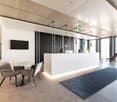 Reception desk, chairs, monitor, glass doors, carpet, tables, lamps