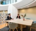 oval meeting table, 4 chairs, white and brown shelves, flowers, carpet, balcony