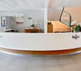 Curved reception desk, white and brown interior, flower vases, staircases in the background