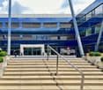 Business center with modern architecture, multiple floors, glass facade, entrance with steps, landscaped entrance area