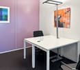 modern minimalist office, white desk, modern lamp, black chairs, colorful paintings on wall