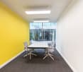 meeting room with a yellow wall, white walls, a large table, grey carpet, ceiling lamps