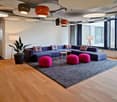 a large area with a rug, couches, tables, lamps, and a potted plant.