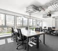 modern office room with large windows, desks, chairs, and air conditioning units