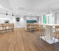 modern kitchen with wooden floors, white walls, large windows, modern bar stools, central island, white cabinets, modern pendant lights