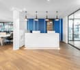 modern office space, white walls, blue accent wall, wooden floors, glass doors, reception desk, office chairs, desks, pendant lights