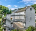 multi-level building, multiple stairs, parking lot, large window panels, raised ground floor
