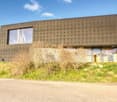 Modern house, raised ground floor, large windows, concrete exterior, green grass, view of the surrounding area