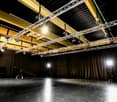 Empty room with black floor, wooden ceiling, black curtains, green screen, lighting equipment