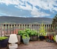 wooden balcony, various potted plants, white lamp, wooden railing, mountainous landscape