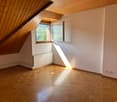 empty room, wooden ceiling, wooden floor, wall-mounted radiator, window, bright sunlight