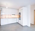 modern kitchen, white cabinets, tiled floor, wooden countertops, built-in oven, sink with faucet, dishwasher, washing machine