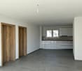 Empty room, white walls, wooden doors, gray floor, white kitchen cabinets, stainless steel faucet, kitchen window