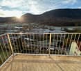 Metal railings, panoramic view of the mountains and village, clear skies with sun