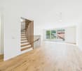 large room, hardwood floor, white walls, staircase leading to upper floor, large glass doors, balcony