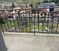 Balcony with railings, overlooking a small town with many houses and greenery