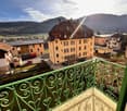 Apartment building with several buildings, balcony with green railing, mountain view