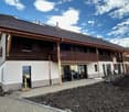 New construction, wooden exterior, modern design, solar panels on roof, wooden balcony, glass doors and windows