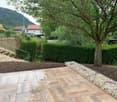 stone paving, stone wall, rock bed, hedges, trees, background with houses and mountains