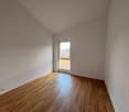 Empty room with white walls, wooden floor, glass window, power outlet