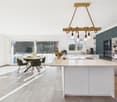 modern kitchen with island, dining table, green chairs, large windows, balcony, view of trees