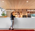 white reception desk, wooden ceiling, red carpet, plant, large windows, desk lamps