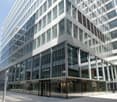 Multi-story glass and steel commercial building with a ground floor entrance and signage for 'Spaces', indicating it is likely an office or co-working space.