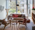Spacious office with large windows overlooking a balcony, modern furniture including a sofa, armchair, and coffee tables, and a motivational message on the wall