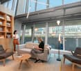 Contemporary interior, exposed ceiling, glass windows, wooden furniture, cozy seating area, reading lamp, natural light