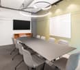 Meeting room with long table, chairs, white whiteboard, TV on the wall, modern lighting, gray carpet.