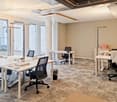 modern office with white desks, black chairs, trash can, glass doors, white walls, beige carpet