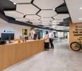 Open area with reception desk, modern ceiling design, large monitor, office bikes, wooden wall with text