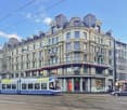 multi-story commercial building, glass windows, modern tramway, shops on ground floor