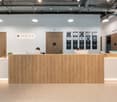 modern reception area, wooden desk, white countertops, monitors, closed doors, hanging lamps, open ceiling